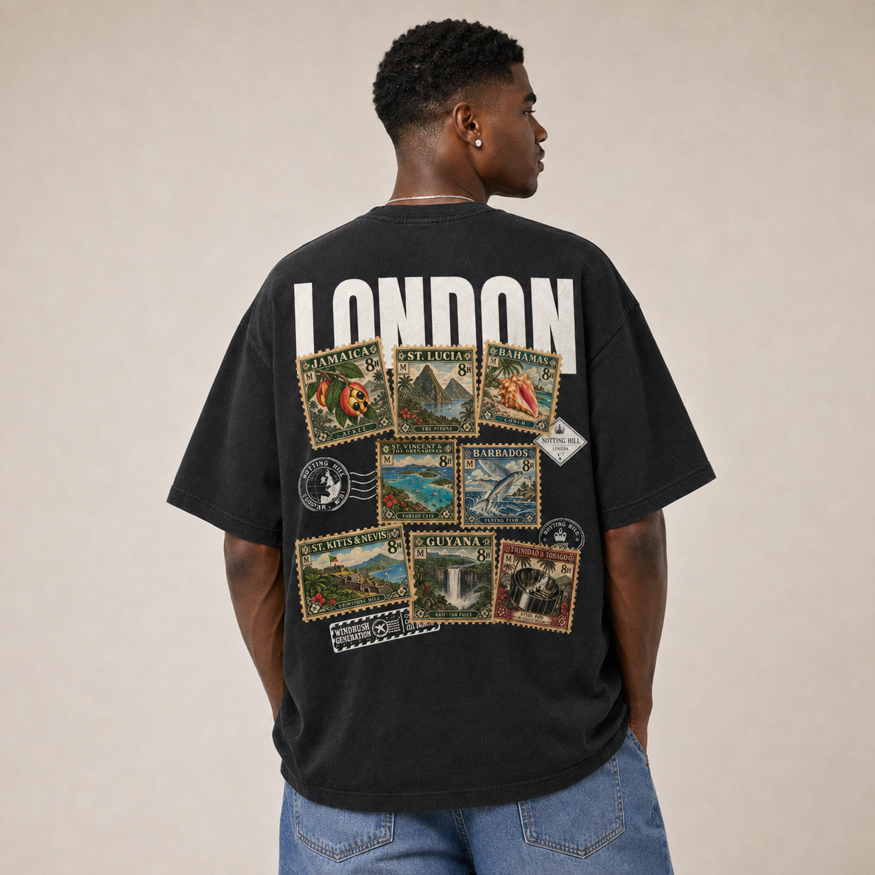 A man seen from behind wearing the washed black Maknesan tee, the LONDON wordmark printed in white above a collage of Caribbean postage stamps.